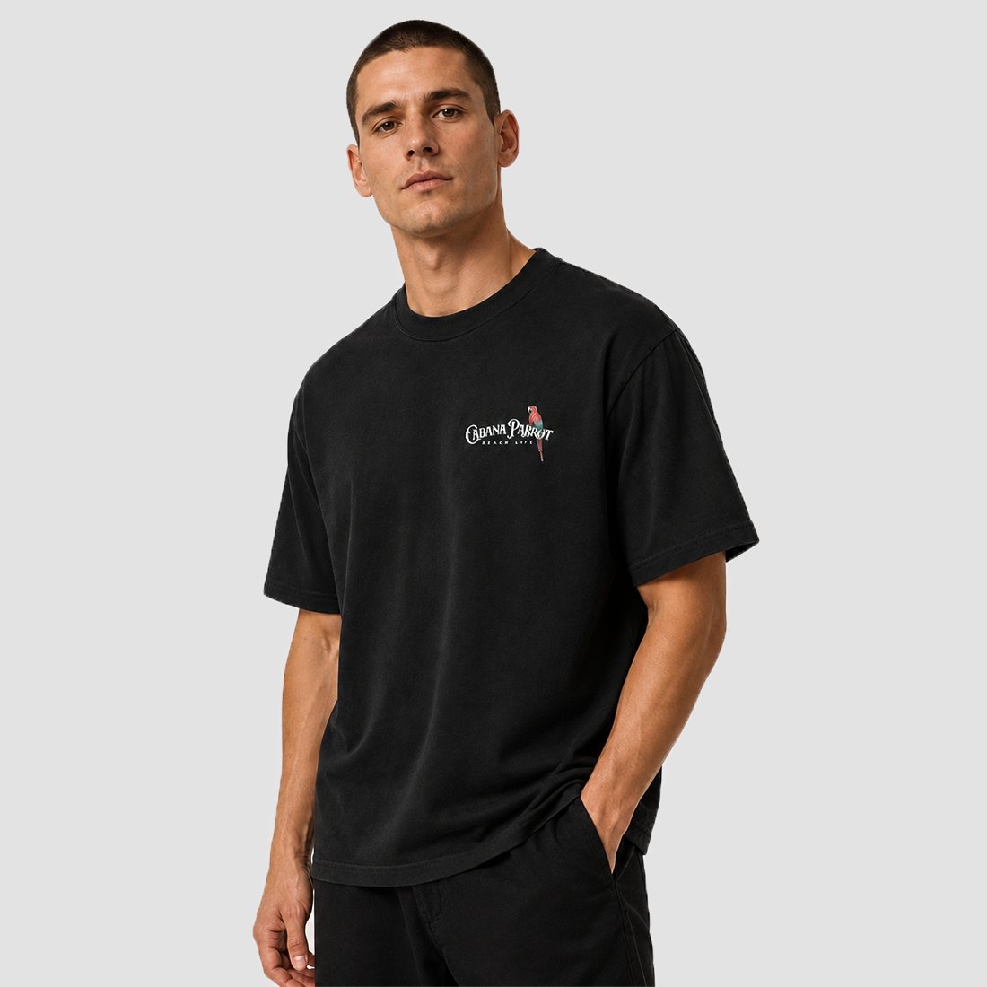 Man wearing black unisex beach tee with parrot logo, soft comfy style for casual wear